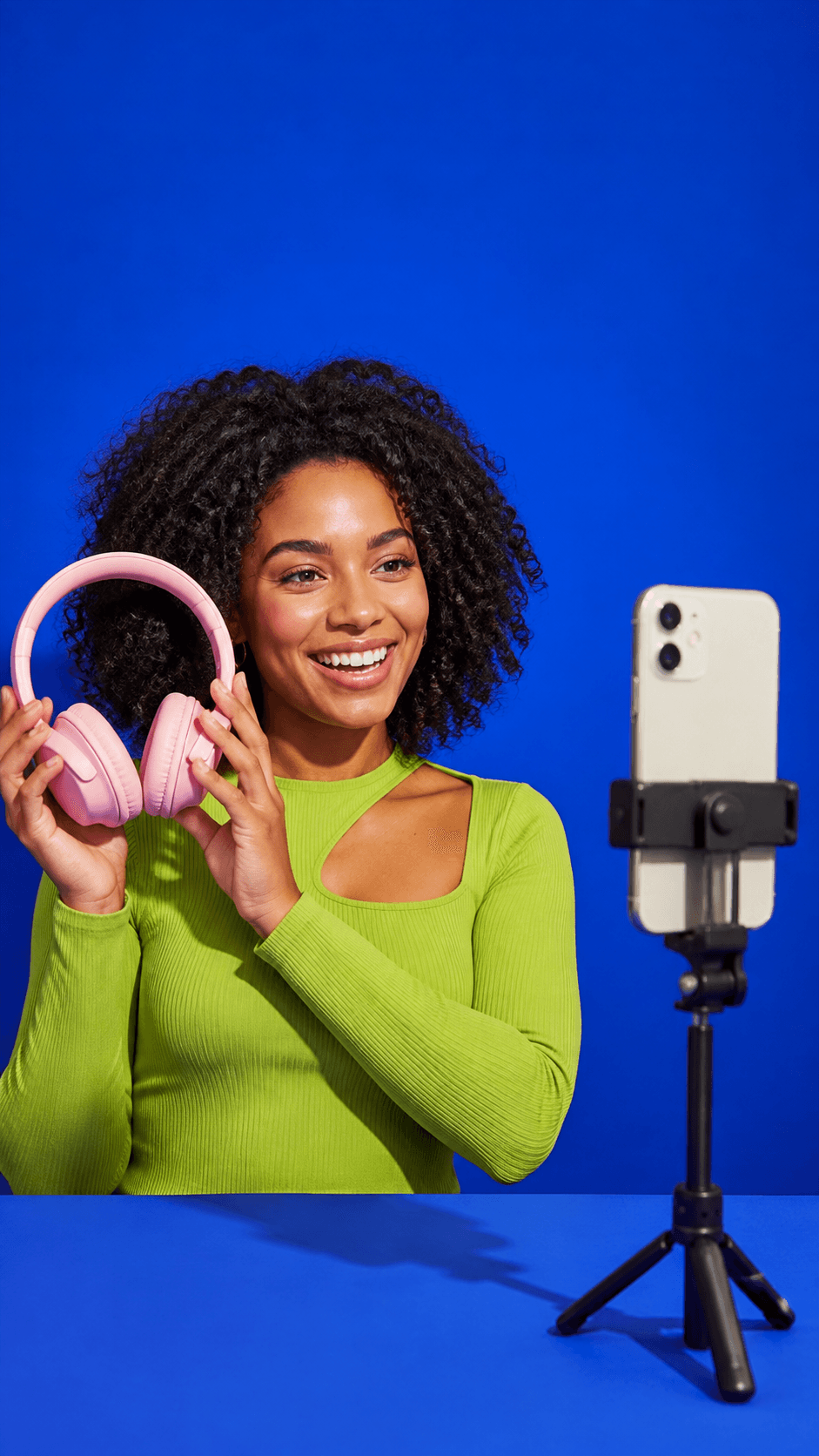 Original AI-generated concept photograph of a creator demonstrating a compact camera in a pink and cobalt studio
